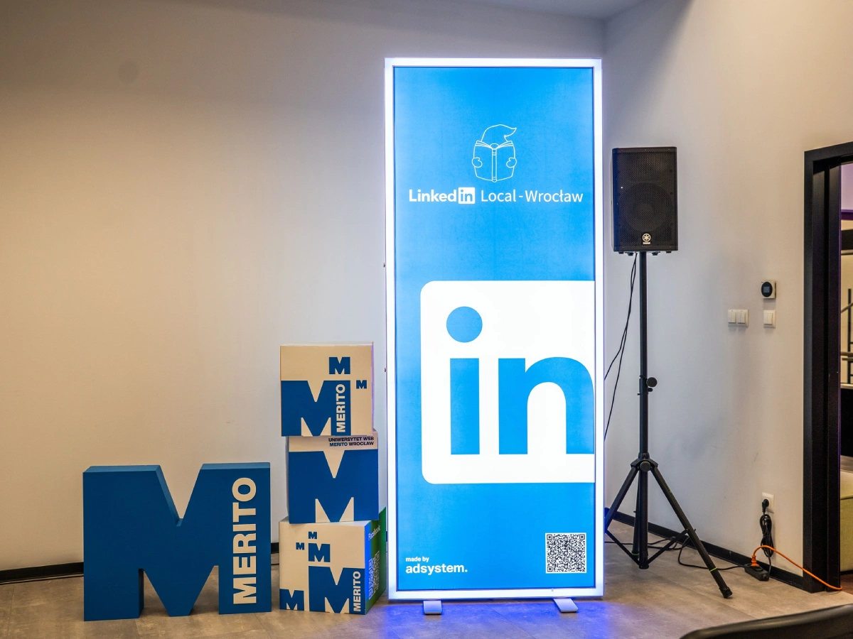 Kaseton podświetlany z grafiką LinkedIn Local – Wrocław, logotyp platformy LinkedIn, oznaczenie „made by adsystem”, obok ekspozycja z literami i kostkami z logo MERITO.