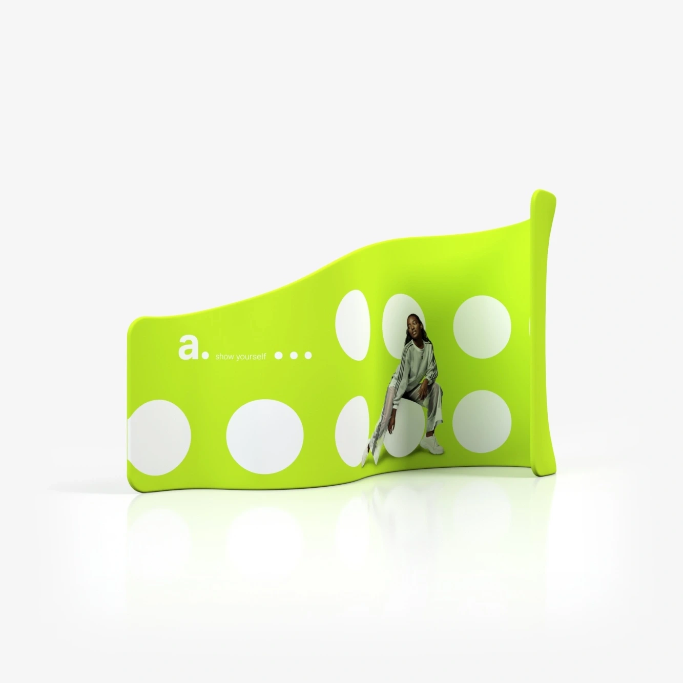 Ścianka tekstylna o nieregularnym, falującym kształcie z neonowozielonym tłem, dużymi białymi kropkami i grafiką kobiety w zielonym stroju, siedzącej na tle konstrukcji.