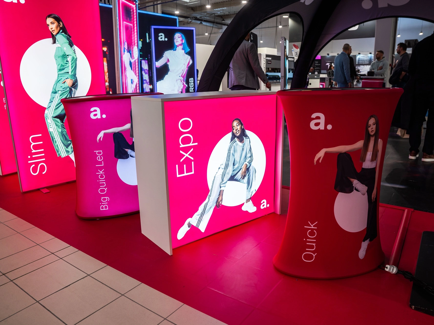 Stoisko targowe z podświetlanymi trybunkami i ściankami tekstylnymi prezentującymi systemy wystawiennicze adsystem.