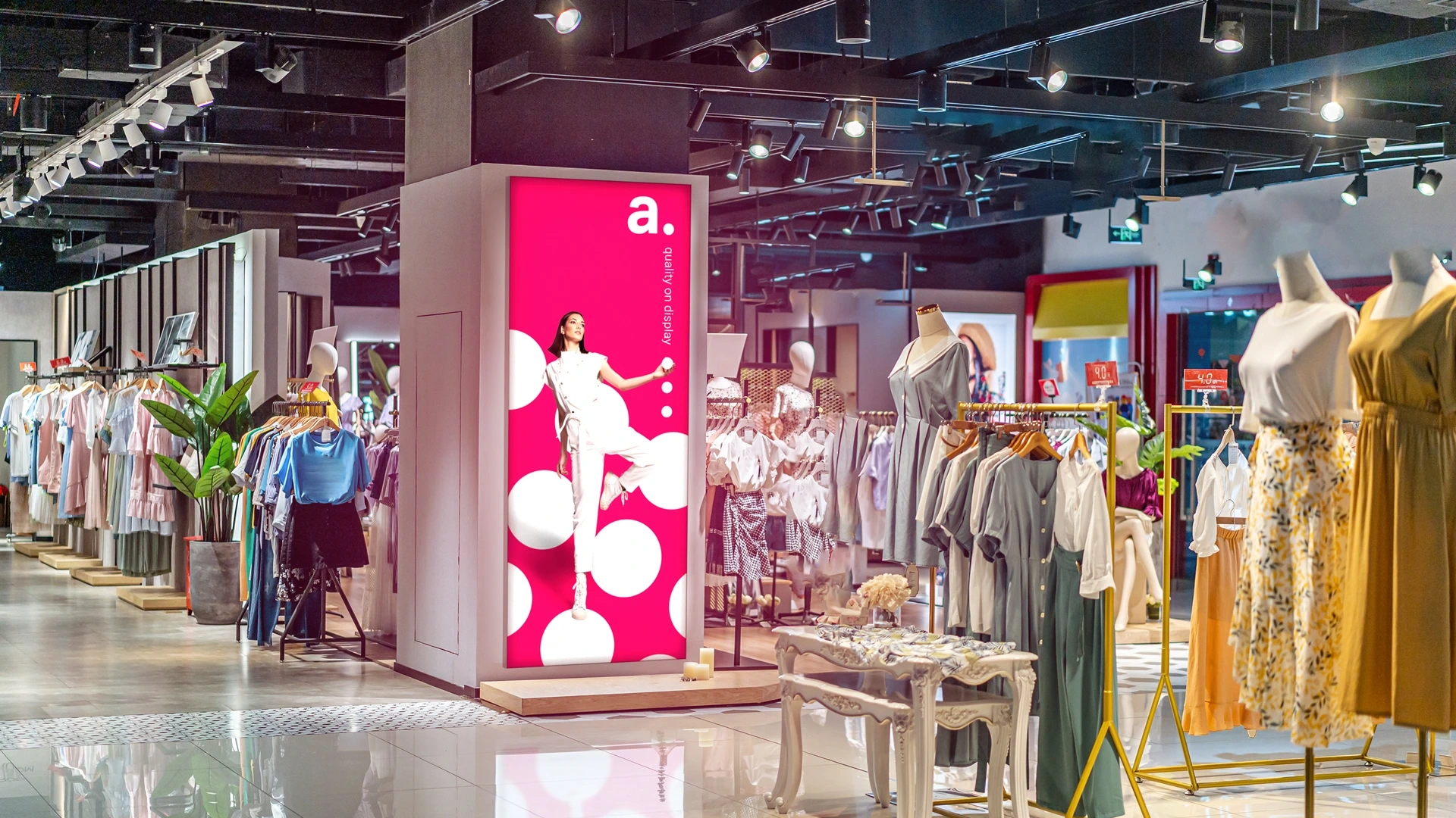 Podświetlany kaseton LED z modową grafiką promocyjną ustawiony wewnątrz eleganckiego butiku odzieżowego w centrum handlowym.