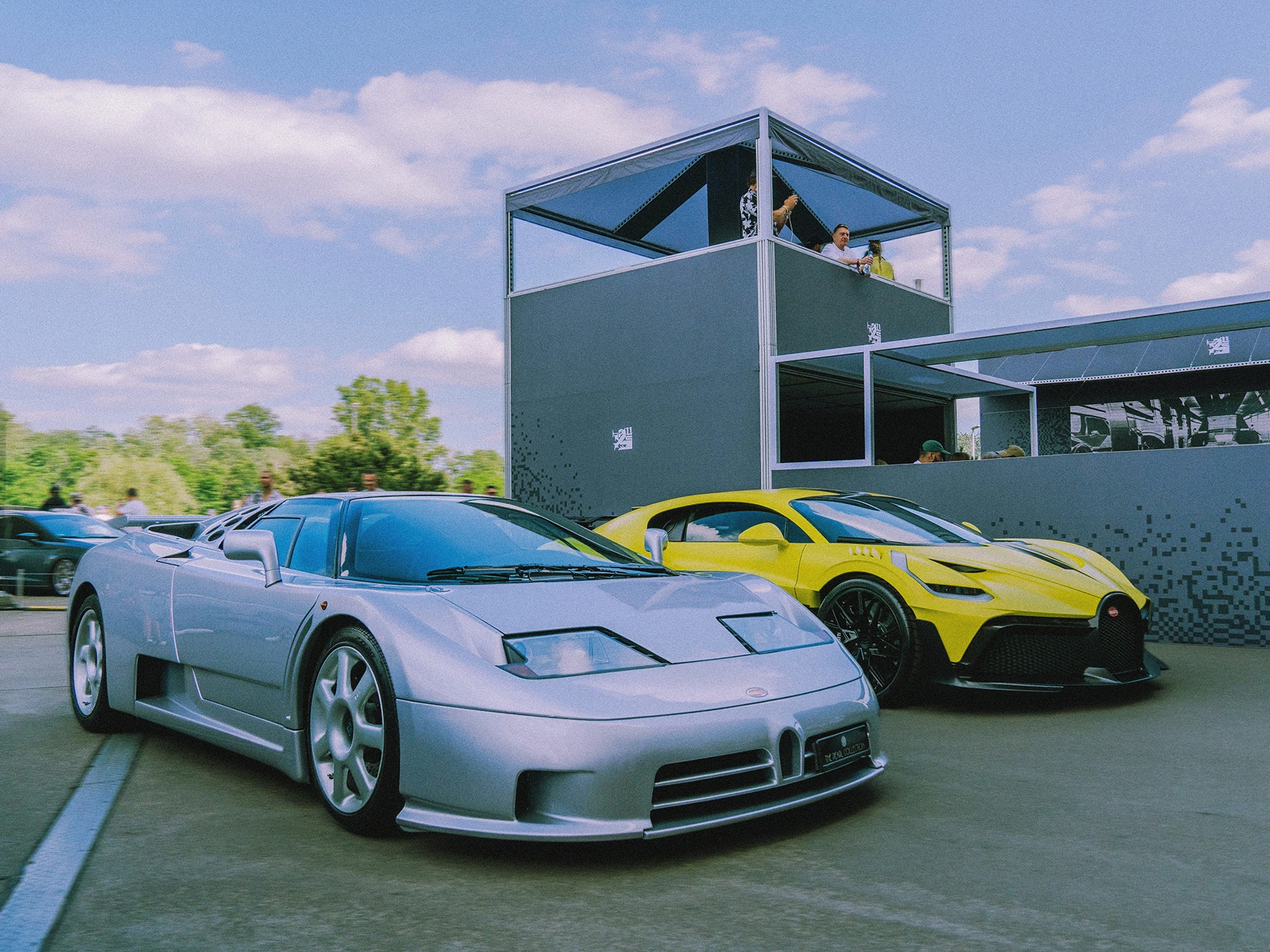 Srebrny i żółty supersamochód Bugatti zaparkowane przed dwupoziomową strefą VIP podczas wydarzenia Ultrace 2025.